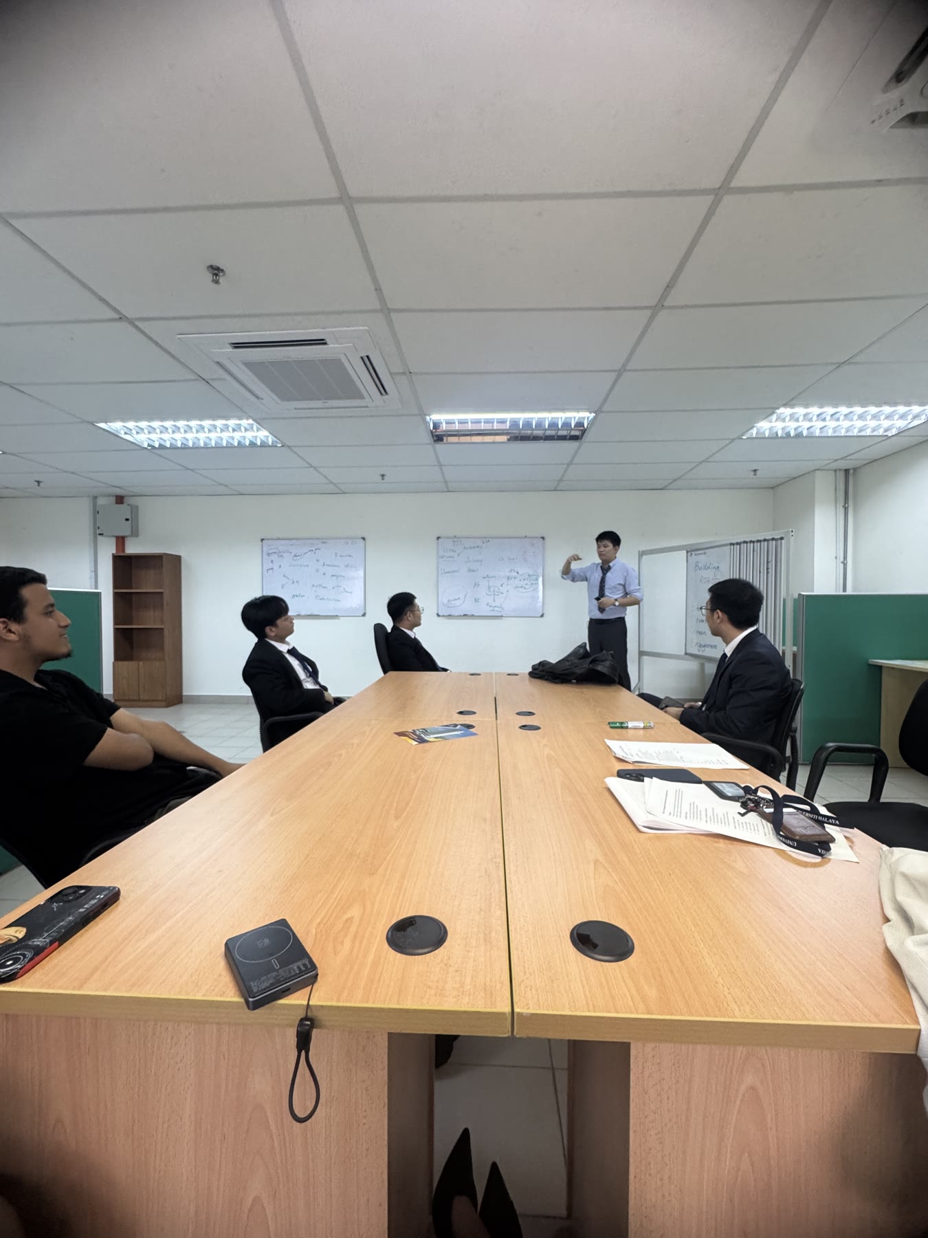 Johnny Chan discussing lab workflow with team members in a coordination room